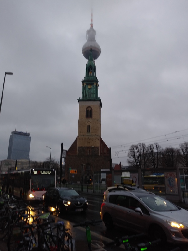 A view from unter den Linden of the cloud-reaching TV Tower looming behind the aged St. Marienkirche church.